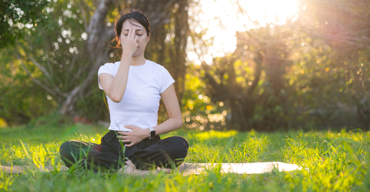 : Foto de uma mulher sentada em posição de meditação.
